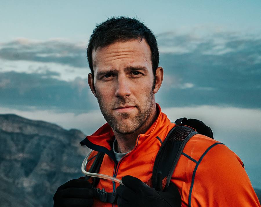 Portrait of Ryan Pyle in an orange jacket in the mountains