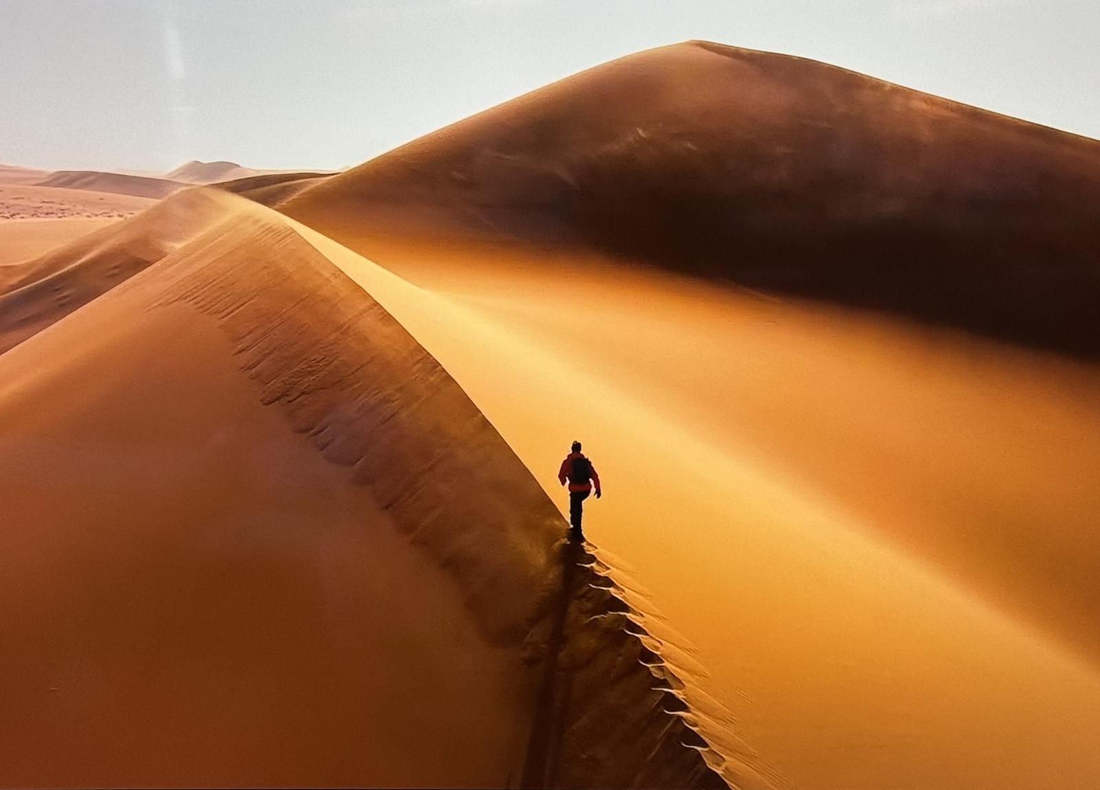 Ryan Pyle walking along the ridge of a sand dune in the Namib desert